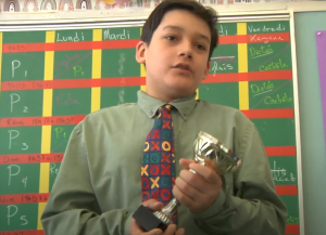 Garçon jouant un homme portant une cravate voyante et tenant un trophée