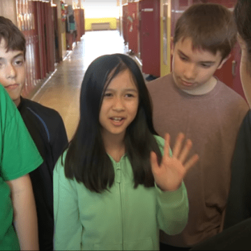 Jeune fille protestant de la main dans un couloir d'école