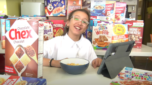 Fillette assise à un bureau entourée de boites de céréales diverses