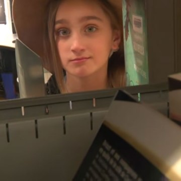 Fille regardant à travers un rayon de bibliothèque